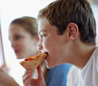 Niño dándole un gran mordisco a la Peter Piper Pizza