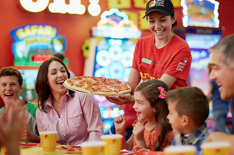 Peter Piper Pizza's Banner of Happy Customers being served a delicious pepperoni pizza by the warm and welcoming Peter Piper Pizza waitress