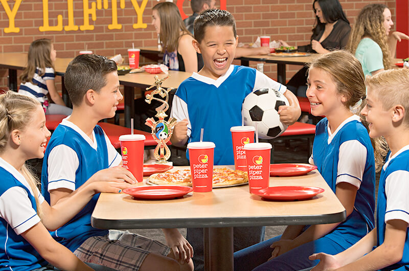 Niños felices disfrutando de su comida en equipo en Peter Piper Pizza